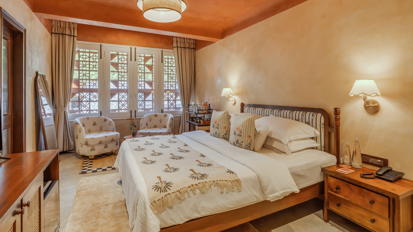 Bedroom at Unseen Boutique Hotel with large bed, patterned bedding, standing mirror, and warm earthy walls.