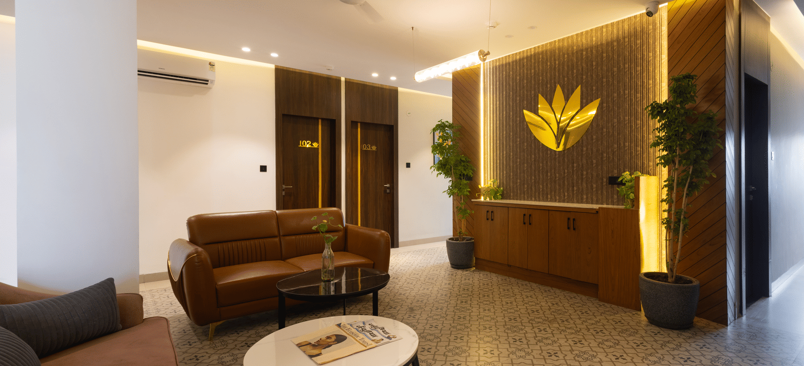 Interior view of the lobby area with a brown sofa and a decorative logo on the wall at Pravasa Stay Luv Kush, Indore.