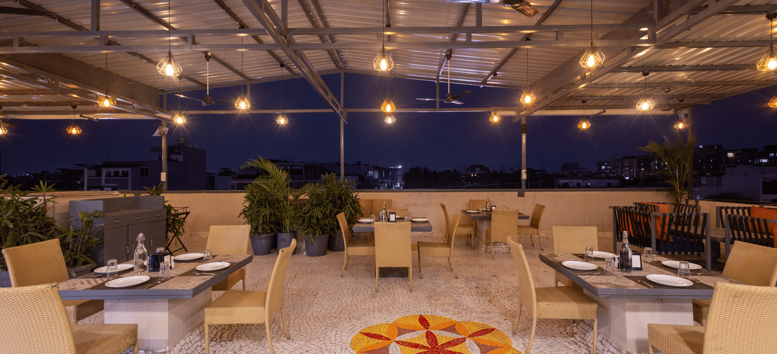 Exterior view of the rooftop terrace with tables and chairs at Pravasa Stay Luv Kush, Indore.