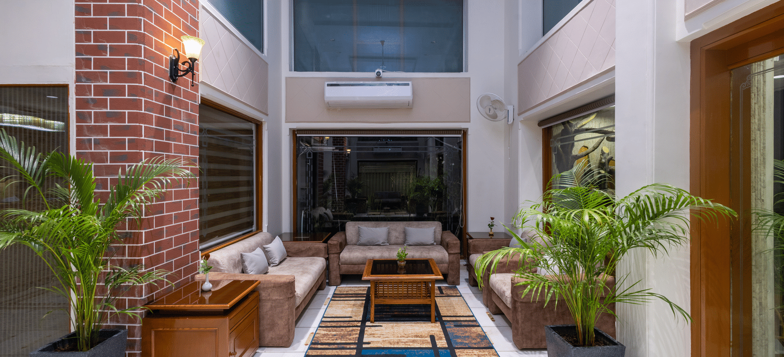 Outdoor courtyard seating with modern furniture, a water feature, and a view of the hotel's brick walls and interior at Pravasa Stay, Vadodara.