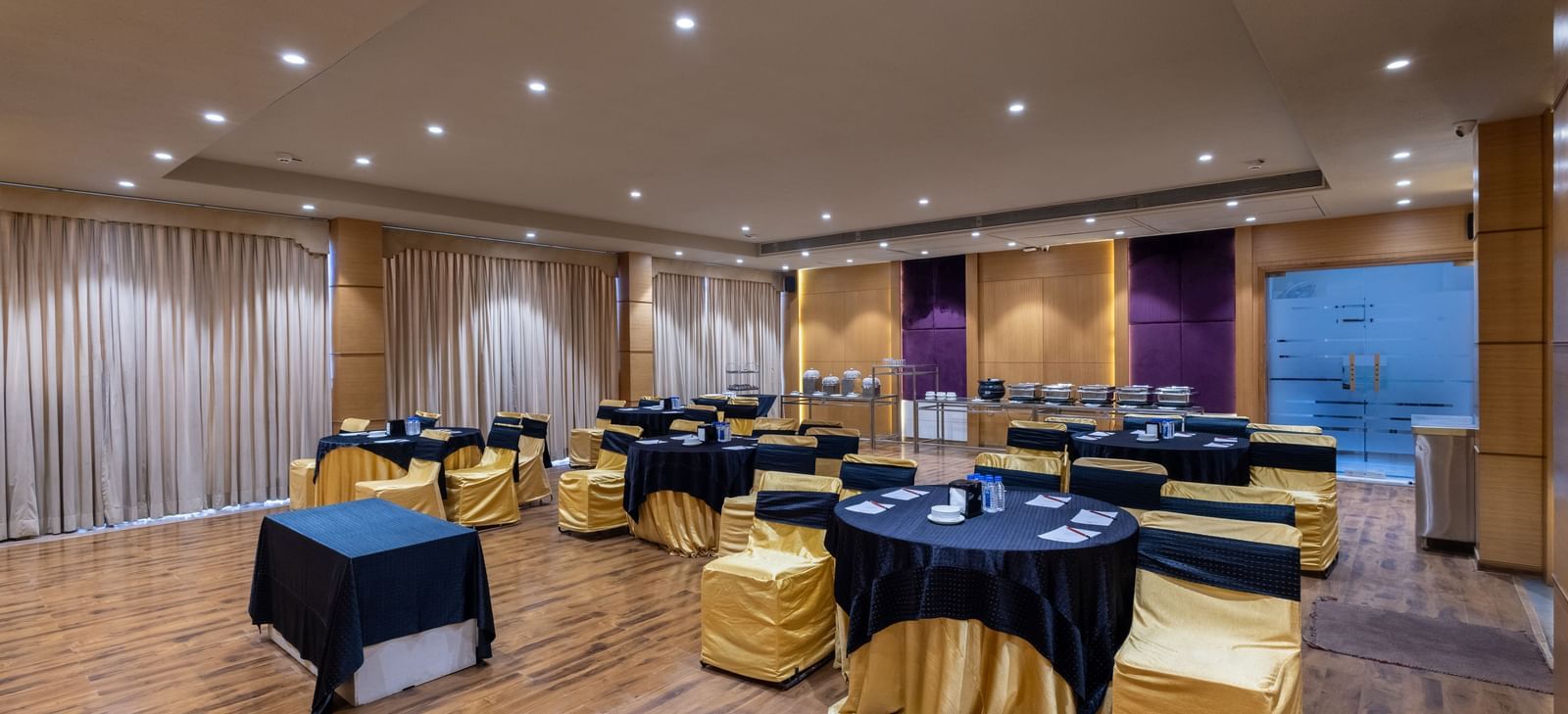 Banquet hall, Iris, with tables in cluster seating arrangment, wooden flooring, seen at Pravasa Stay Vijay Nagar, Indore.