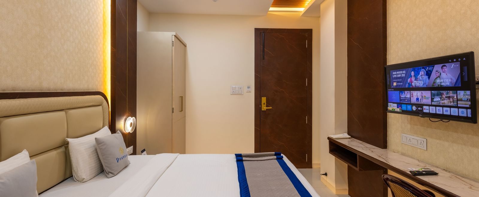 Bedroom with a doublebed, a TV, a chair, ceiling fan, and warm lighting at Pravasa Stay Dewas Naka, Indore.