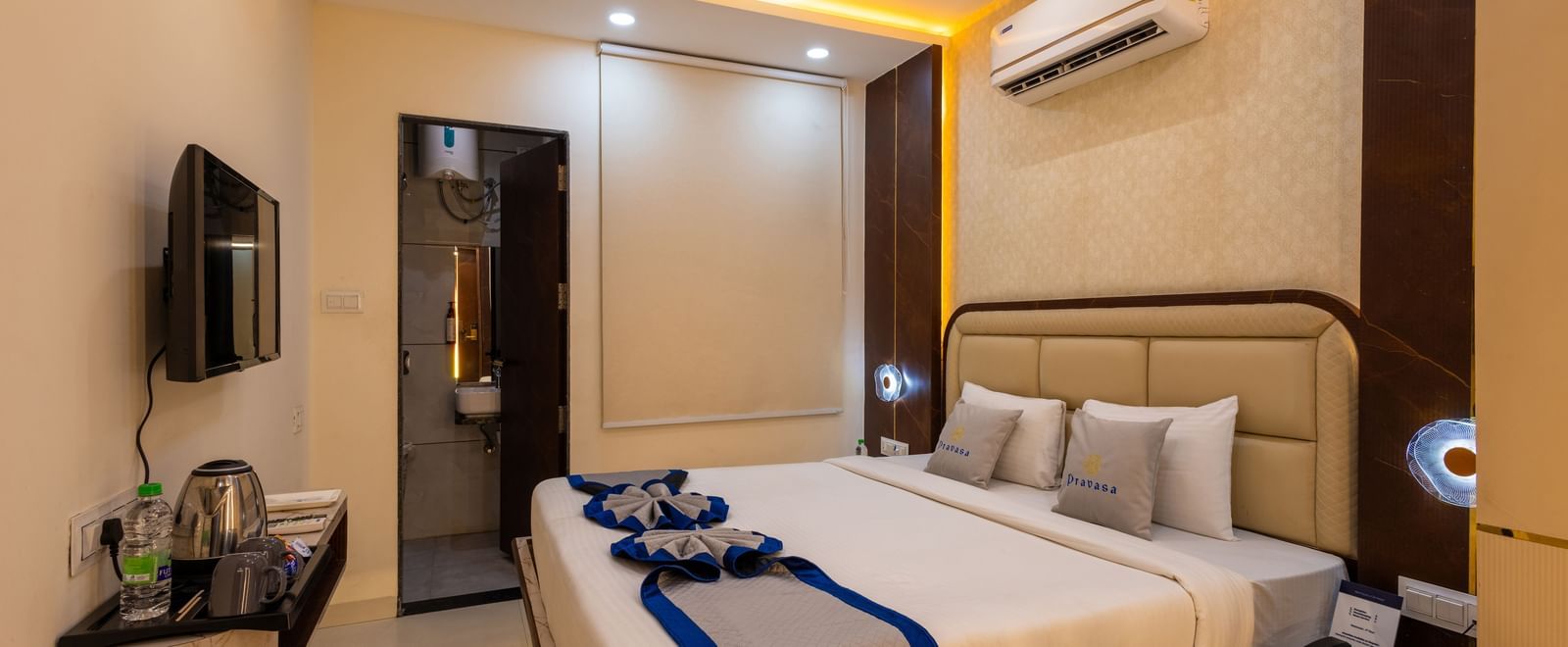 A room with a double bed, TV, ceiling fan, a mirror and wardrobe at Pravasa Stay Dewas Naka, Indore.
