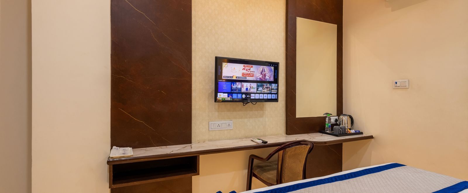 Room with double bed, TV, desk, and wall mirror at Pravasa Stay Dewas Naka, Indore.