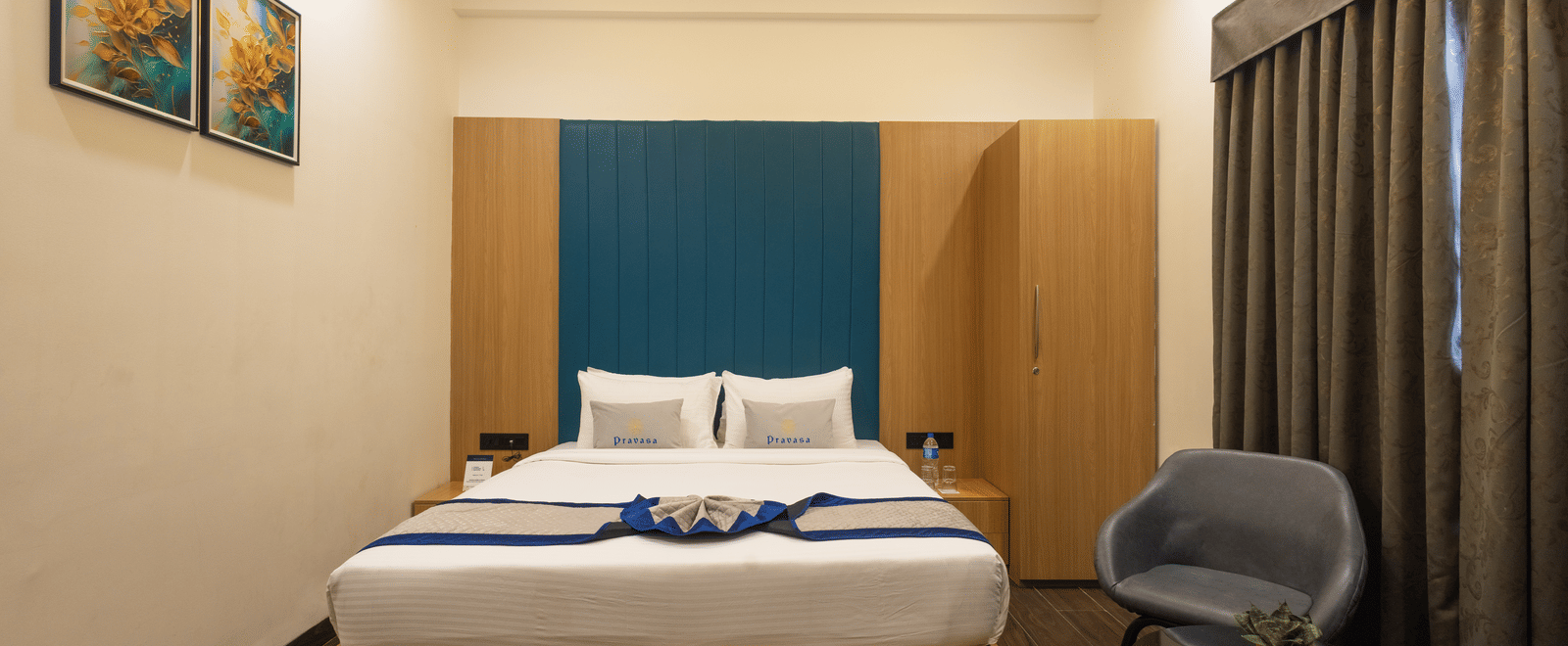Interior view of a guest room with a bed and blue headboard at Pravasa Stay Luv Kush, Indore.