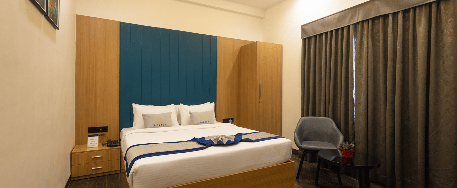 Interior view of a guest room showing the bed and window with closed curtains at Pravasa Stay Luv Kush, Indore.