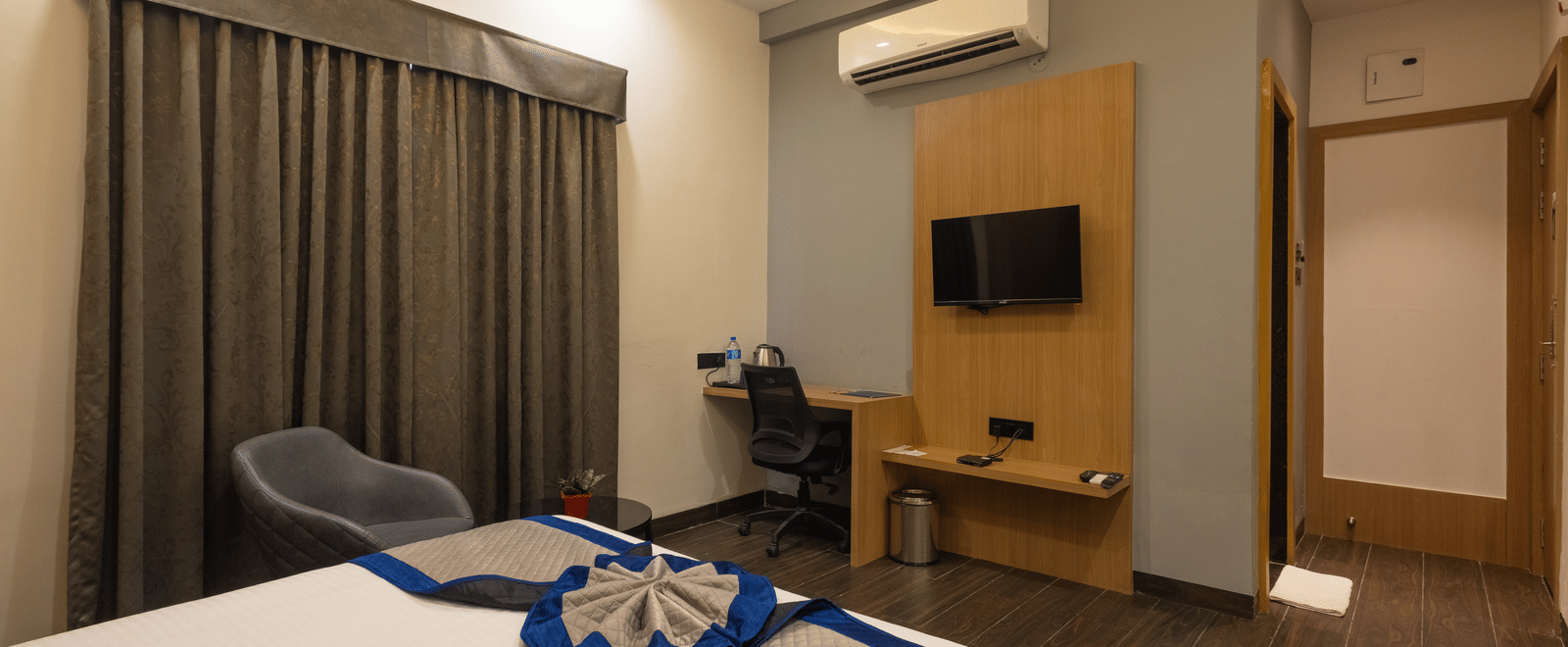 Interior view of a guest room with a bed and a television on the wall at Pravasa Stay Luv Kush, Indore.