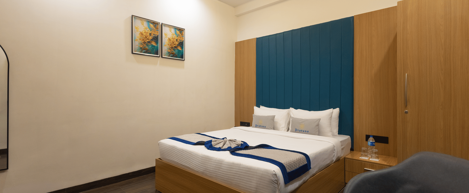 Interior view of a guest room showing the bed, blue headboard, and wooden cabinet at Pravasa Stay Luv Kush, Indore.