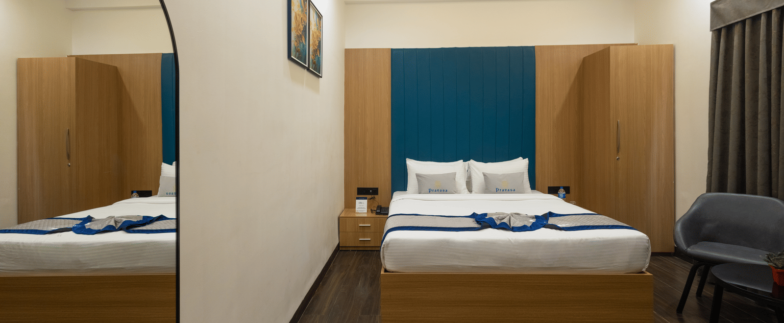 Interior view of a guest room showing the bed, a rounded mirror, and a chair at Pravasa Stay Luv Kush, Indore.