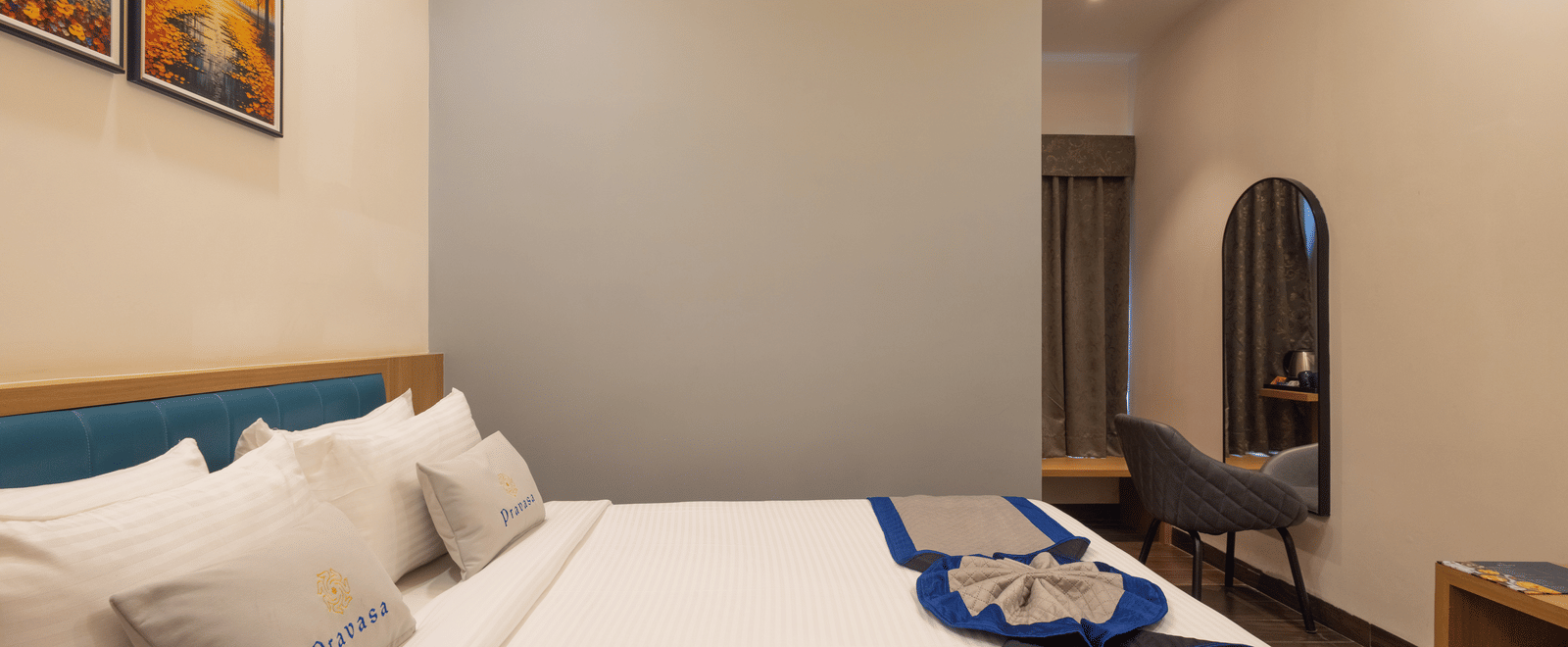 Interior of a guest room showing the bed, chair, and wall art at Pravasa Stay Luv Kush, Indore.