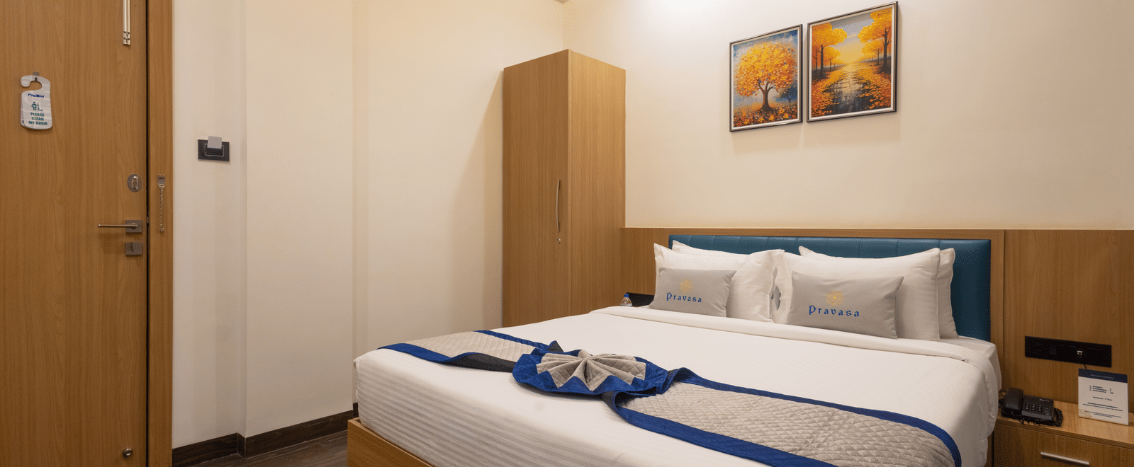 Interior of a guest room showing the bed and wooden cupboard at Pravasa Stay Luv Kush, Indore.