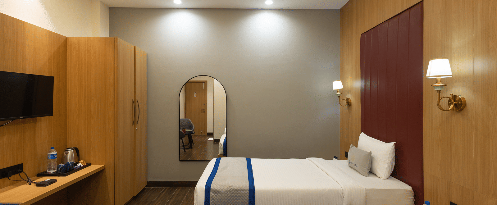 Interior of a guest room showing a twin beds, television, and desk at Pravasa Stay Luv Kush, Indore.