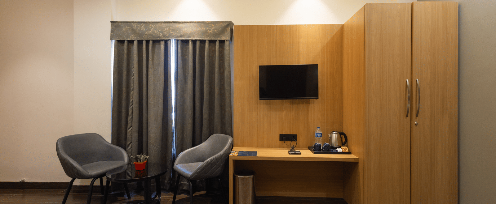 Interior view of a guest room showing 2 single beds, chairs, and a desk area at Pravasa Stay Luv Kush, Indore.