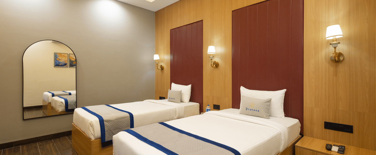 Interior view of a guest room showing 2 single beds and a mirror at Pravasa Stay Luv Kush, Indore.