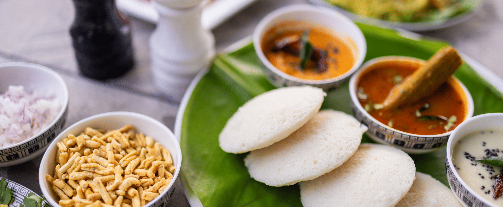View of South Indian breakfast food, including idli, on a banana leaf at Pravasa Stay Luv Kush, Indore.
