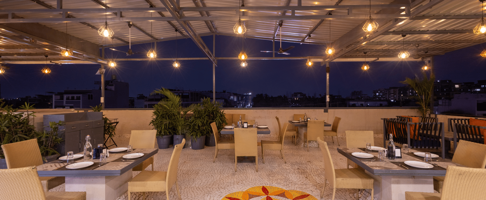 Exterior view of the rooftop terrace with tables and chairs at Pravasa Stay Luv Kush, Indore.