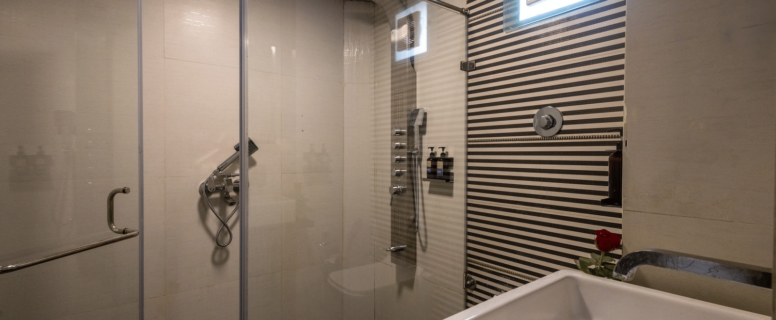 Modern hotel bathroom with a walk-in shower area, large white basin, and striking grey-and-white patterned wall tiles at Pravasa Stay, Vadodara.