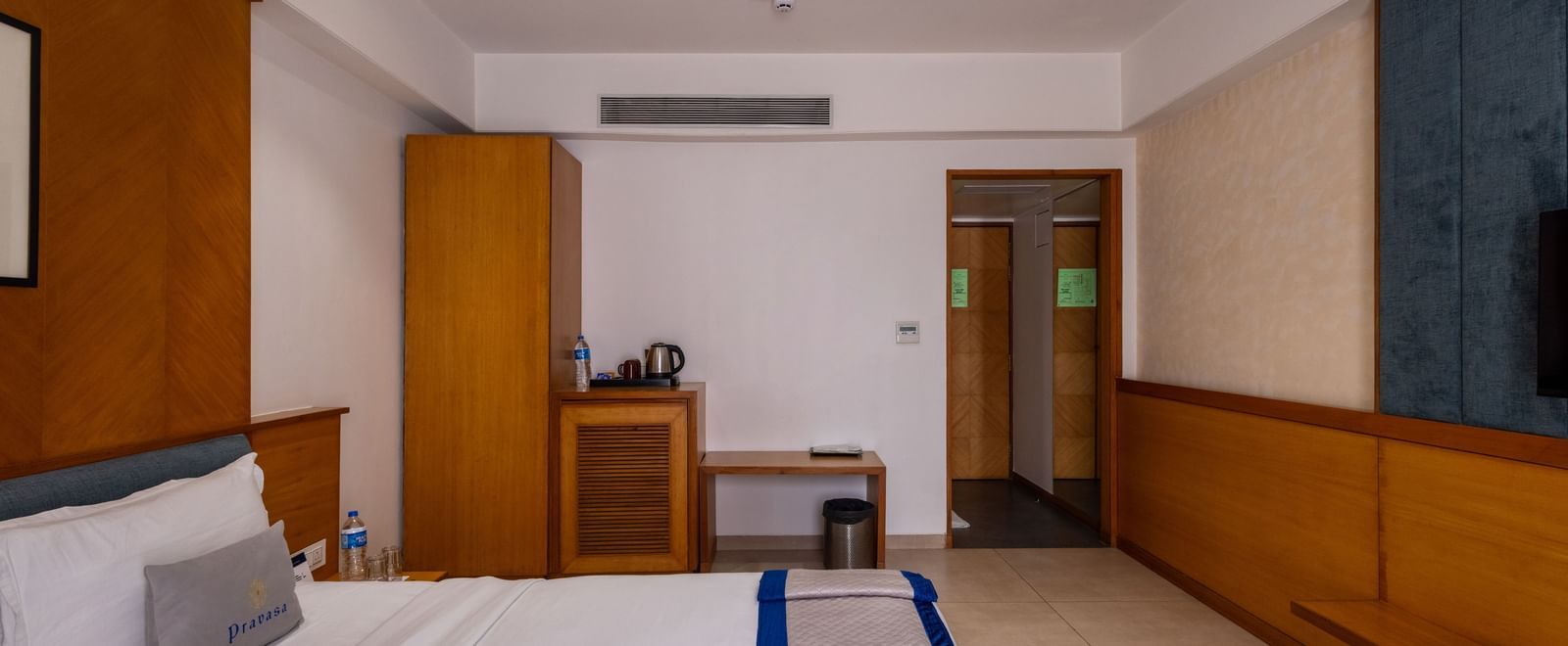 Side view of the bed, wardrobe, desk, and entryway to Executive Premium Room at Pravasa Stay Vijay Nagar, Indore.