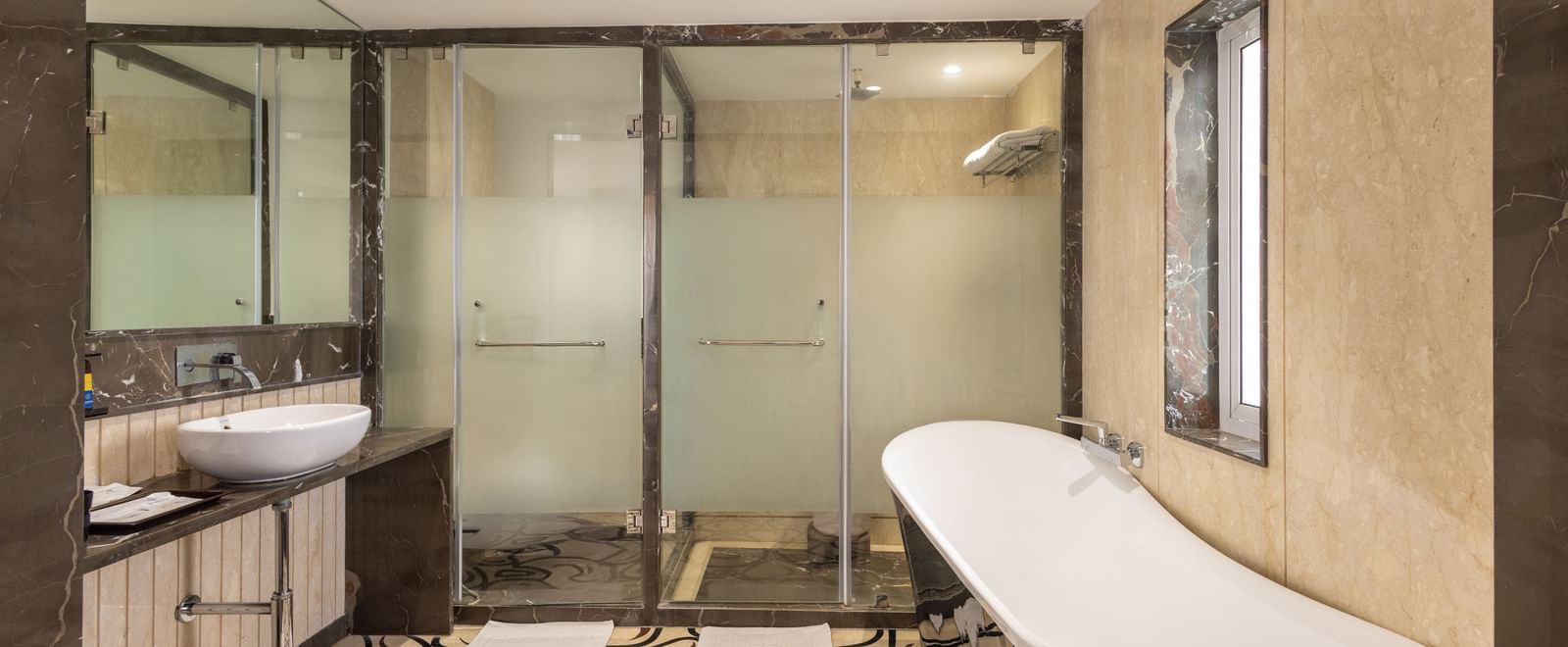 Bathroom of Suite at Pravasa Stay Vijay Nagar, Indore, seen with separated shower area and toiler, a bathtub placed outside opposite the vanity area.