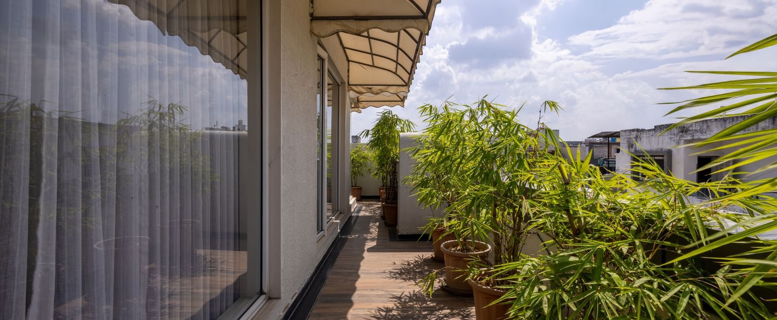 Balcony of a Suite in Pravasa Stay Vijay Nagar, Indore, seen with potted plants, spacious walkway under a cloudy sky.