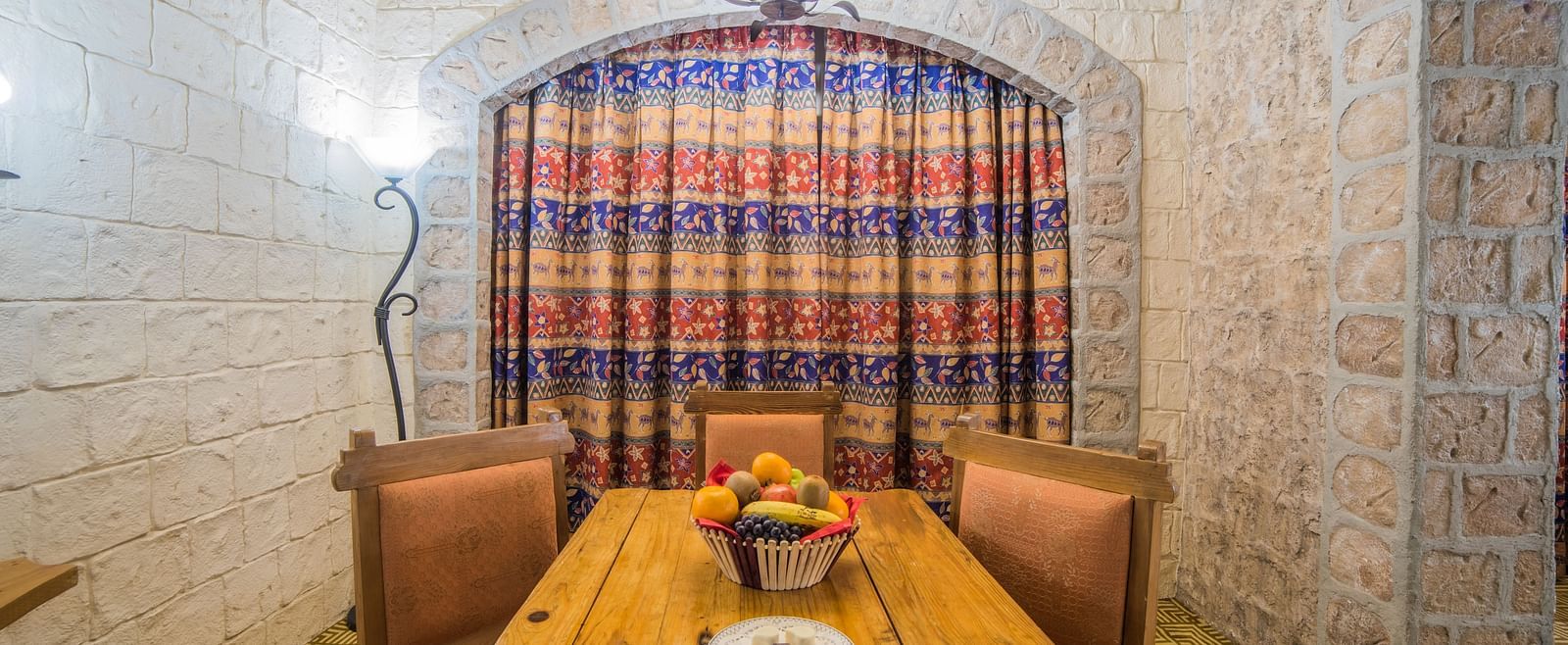 A dining area in a hotel room featuring a robust wooden table and chairs set against a backdrop of a large checkered curtain at  Sitara Luxury Hotel in Hyderabad near Ramoji Film City.