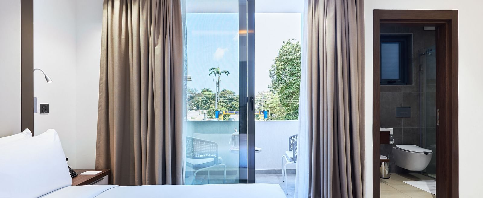 A large bed next to a large window with an outside view in Executive Suite at The Pelican Hotel, Accra.