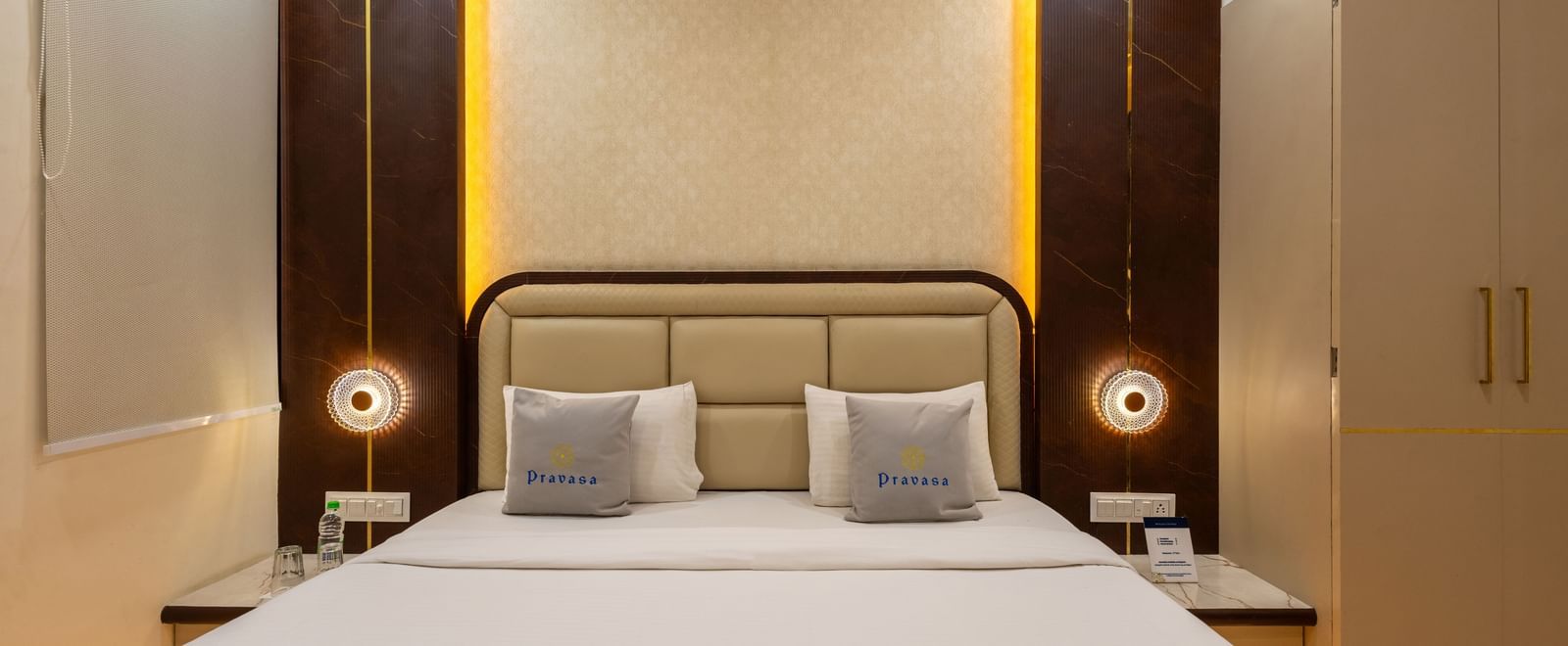A double bed with headboard, side lamps, and wardrobe at Pravasa Stay Dewas Naka, Indore.