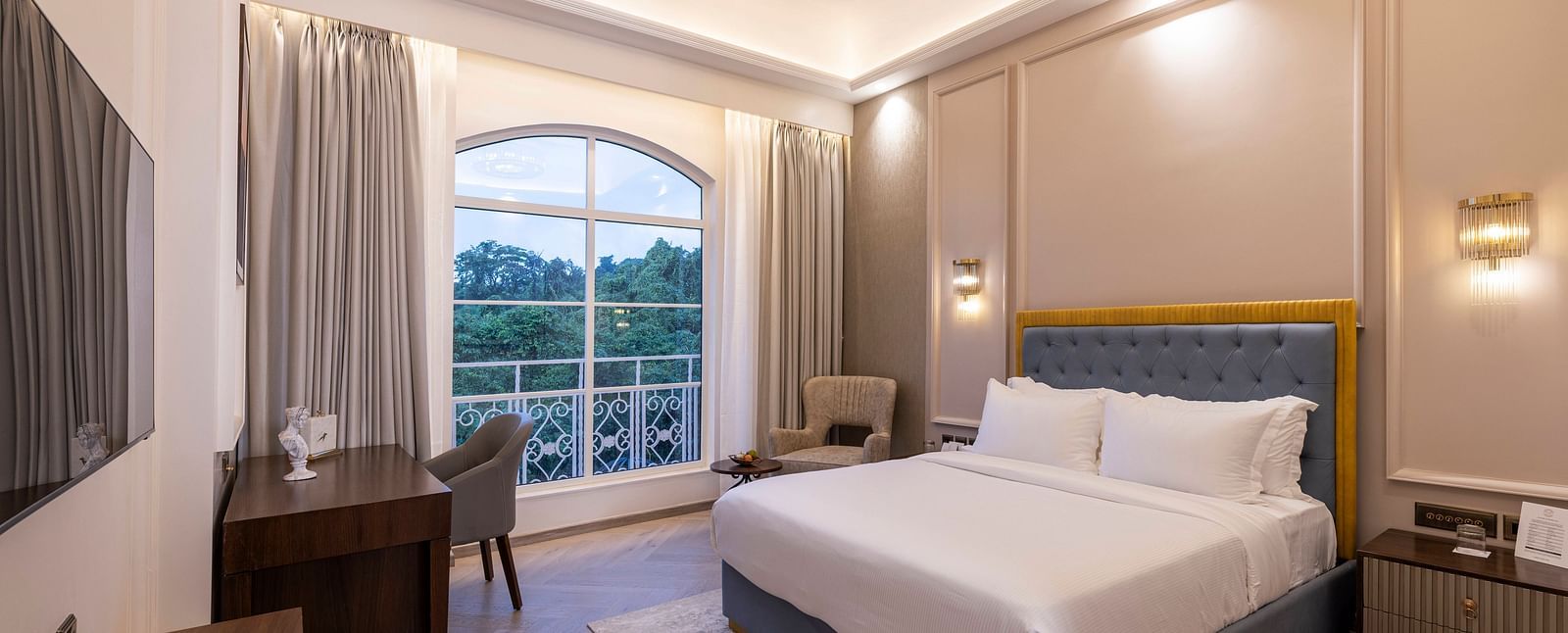 Corner view of the Deluxe Room featuring a double bed and a chandelier hanging from the ceiling right above it at Imperial Goa.