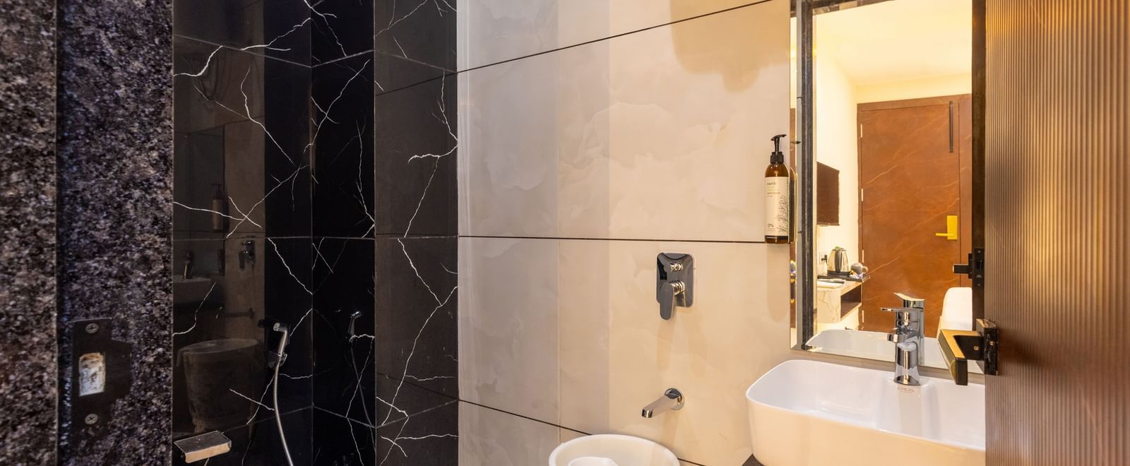 Bathroom with a toilet, washbasin, and black tiled section at Pravasa Stay Dewas Naka, Indore.