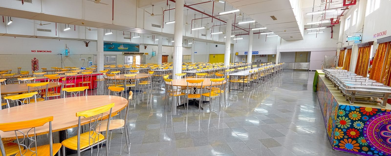 A bright cafeteria with round tables at Sahara - Family Dining in Hyderabad.
