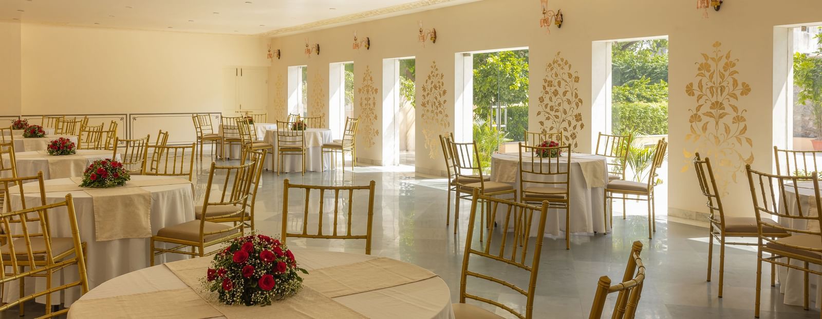 A banquet hall with multiple round tables and chairs, possibly at Royal Heritage Haveli, ready for an event.