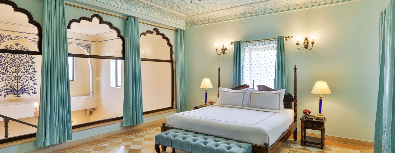 A well-appointed bedroom at Royal Heritage Haveli with a large bed, light blue curtains, and a ceiling fan.