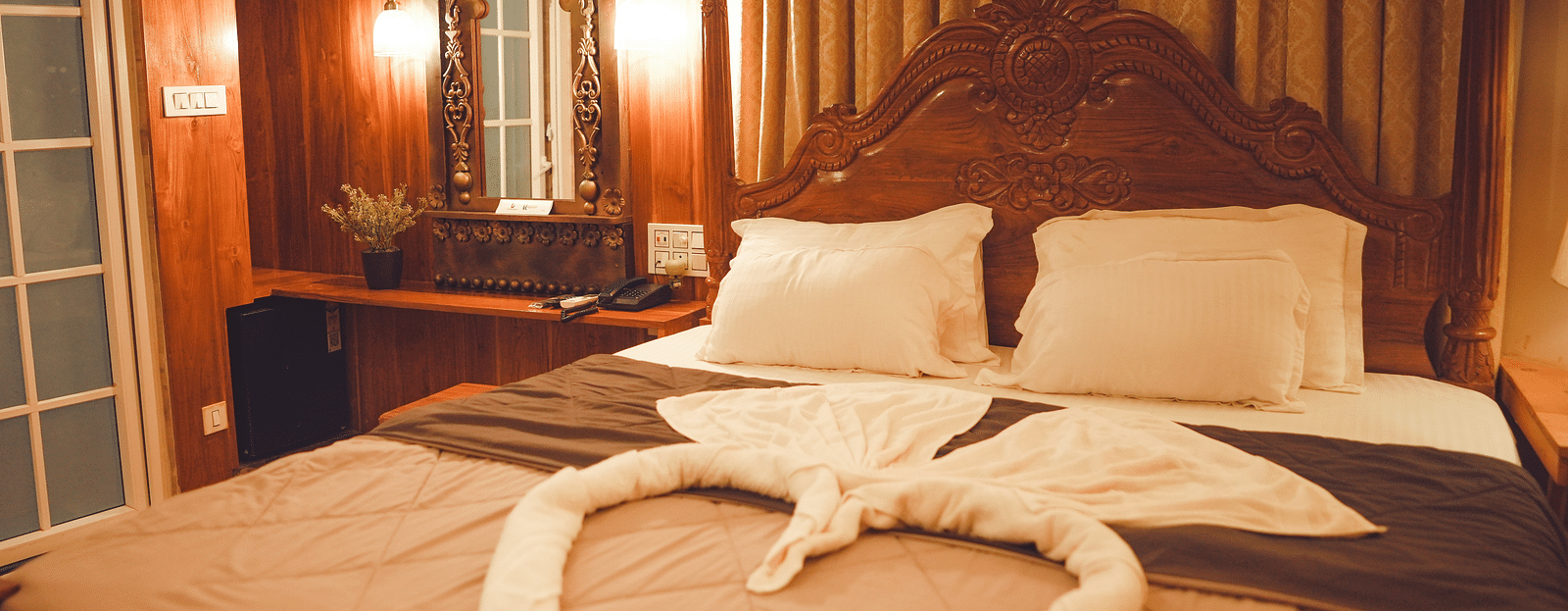 full view image of the comfortable king size bed with a huge wooden headboard at the far end of the bed