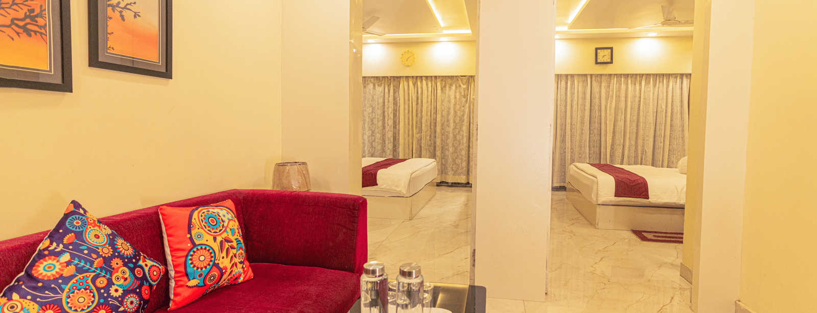 A suite at Hotel Seagull Digha featuring a living area with a sofa and table, and 2 beds in separate rooms visible through open doorways.