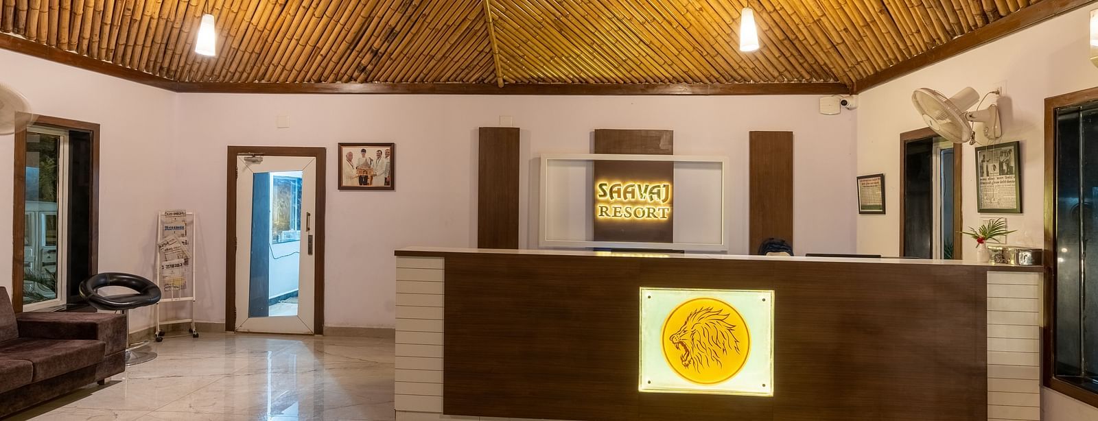  The reception area with a wooden desk, a newspaper stand, and framed photos and achievements on the wall.