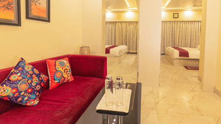 A suite at Hotel Seagull Digha featuring a living area with a sofa and table, and 2 beds in separate rooms visible through open doorways.