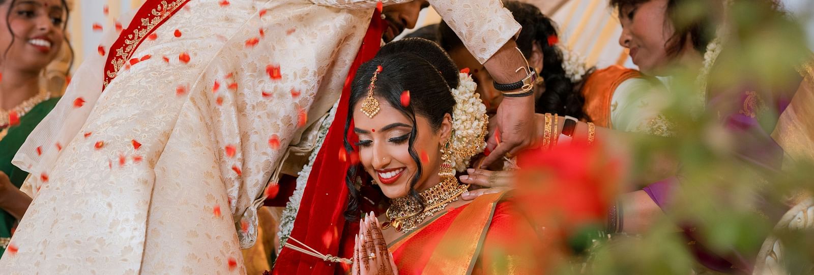 The broom tying a mangalsutra (sacred matrimonial thread) around the bride's neck as she joins her hand in prayer.