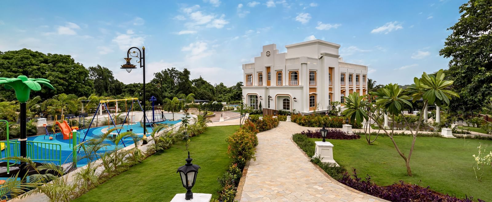 An outdoor play area for kids along side a pathway leading to the facade of Imperial Goa.