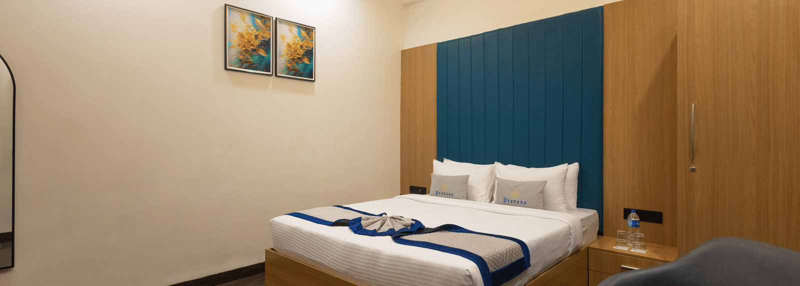 Interior view of a guest room showing the bed, blue headboard, and wooden cabinet at Pravasa Stay Luv Kush, Indore.