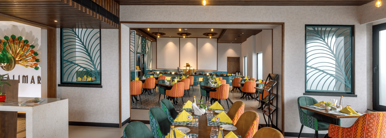 Dining space at Shalimar Restaurant in Zibe Luxe Hyderabad by GRT Hotels, offering colourful seating, ceiling lights, artistic decor, and best food in Hyderabad.