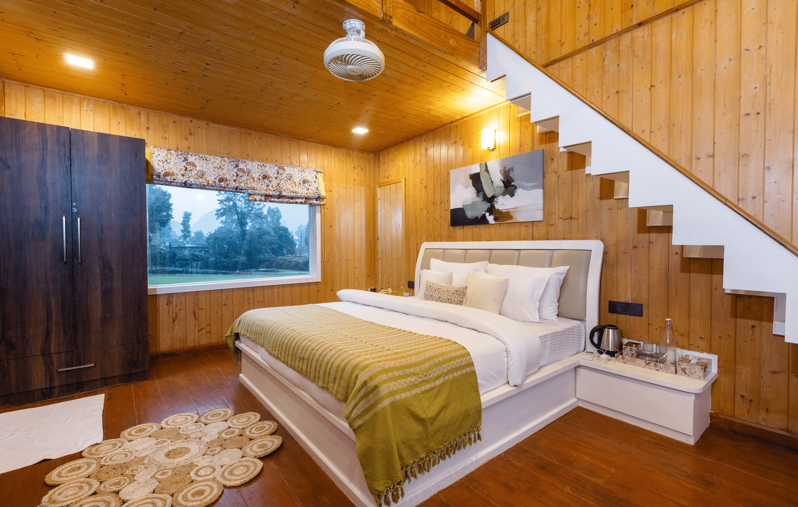 A loft-style bedroom with a bed tucked beneath an open-tread staircase and warm wooden interiors - Megha Resort & Villas, Dehradun