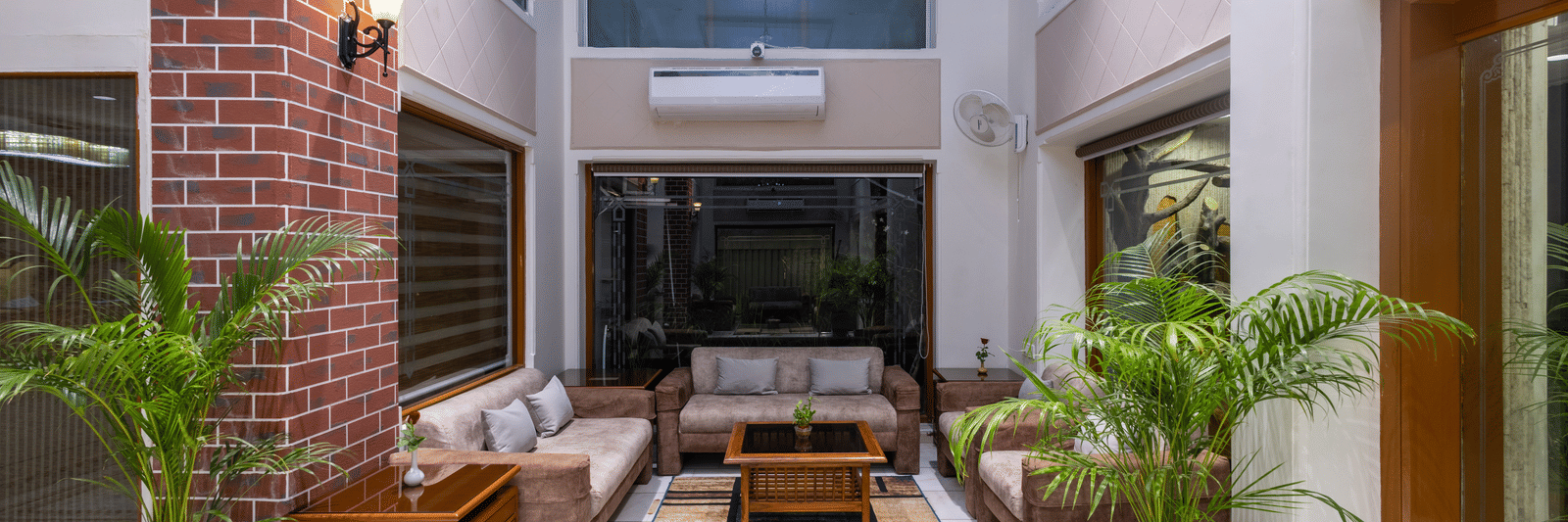 Outdoor courtyard seating with modern furniture, a water feature, and a view of the hotel's brick walls and interior at Pravasa Stay, Vadodara.