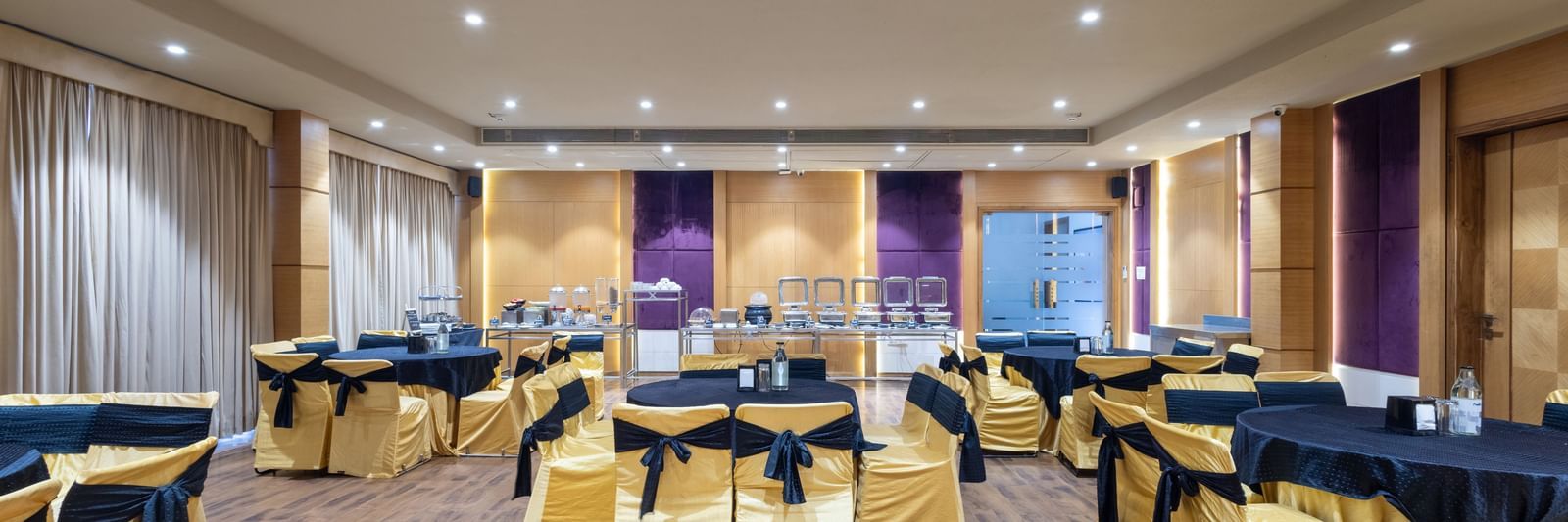 Banquet hall, Iris, with tables in cluster seating arrangment, wooden flooring, seen at Pravasa Stay Vijay Nagar, Indore.