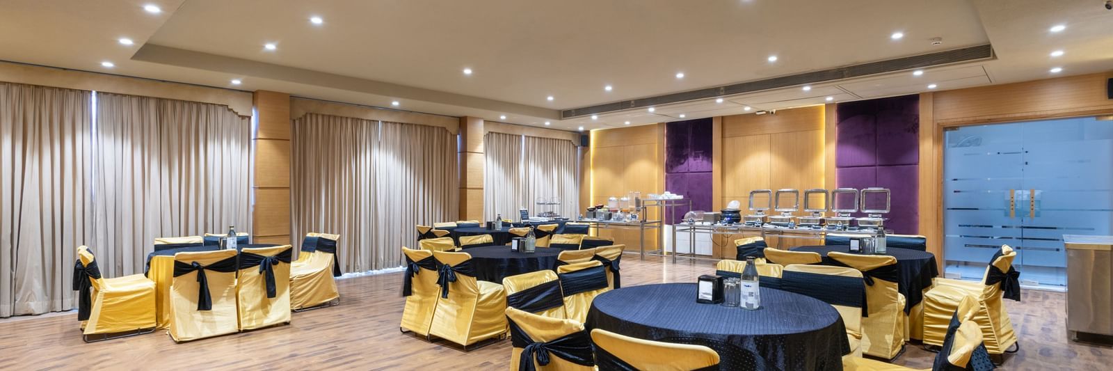 Banquet hall, Iris, with tables in cluster seating arrangment, wooden flooring, seen at Pravasa Stay Vijay Nagar, Indore.