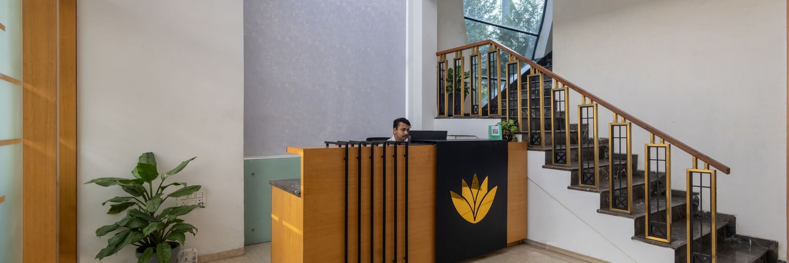 Lobby and reception desk of Pravasa Stay Vijay Nagar, Indore, showcasing a desk, a flight of stairs leading to the floor above, and a floor with patterned tiles in the centre.