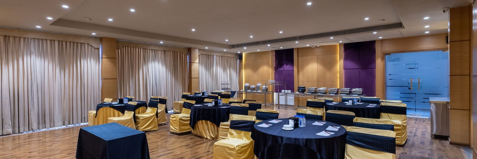 Banquet hall, Iris, with tables in cluster seating arrangment, wooden flooring, seen at Pravasa Stay Vijay Nagar, Indore.