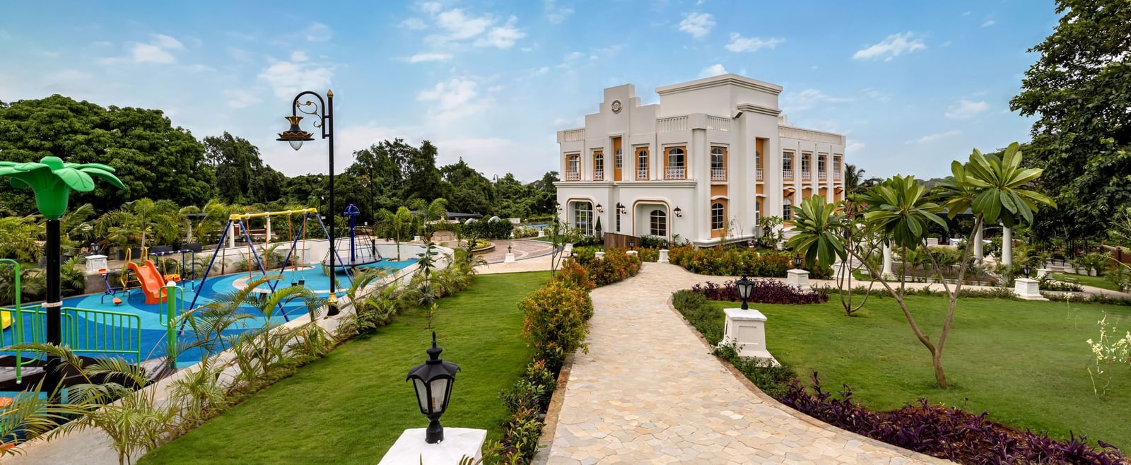 An outdoor play area for kids, alongside a pathway leading to the facade of Miros, perfect for families looking for for a stay in Goa. Resort deals are now available!
