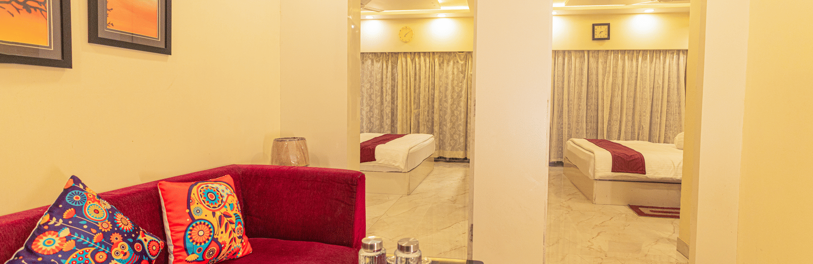 A suite at Hotel Seagull Digha featuring a living area with a sofa and table, and 2 beds in separate rooms visible through open doorways.