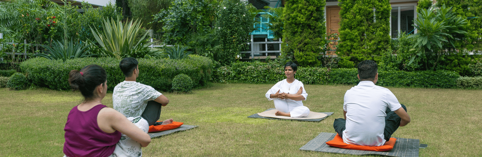 People performing yoga on mats in the garden at Megha Resort & Villas, Dehradun.