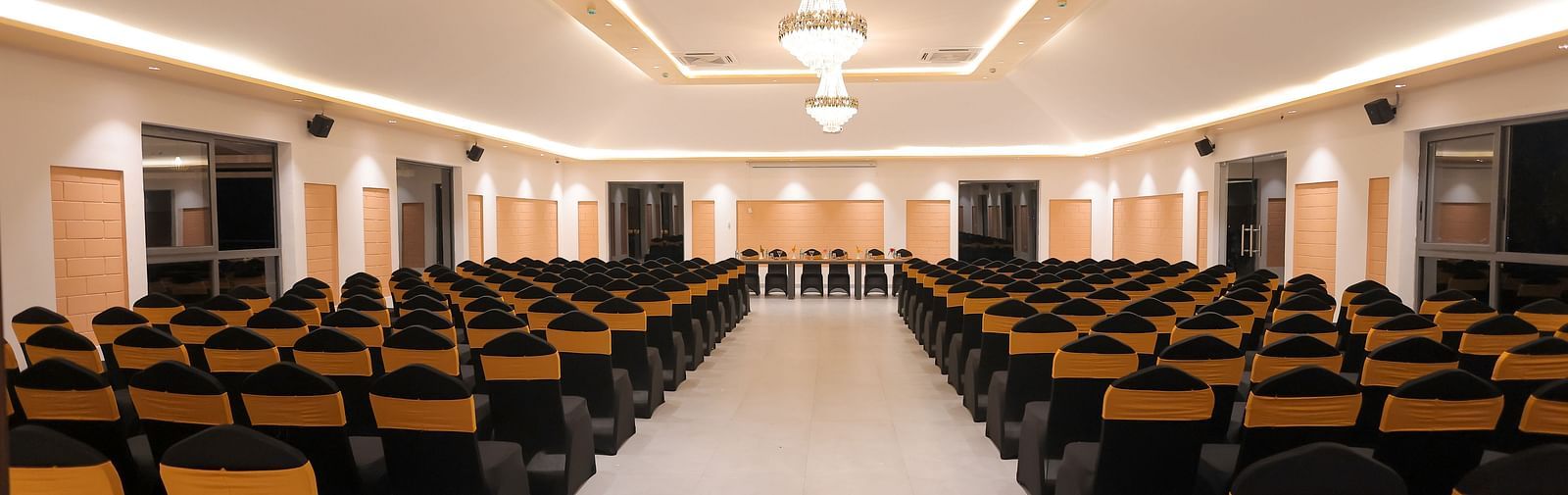 Another view of the main conference hall at Trishvam Symphony, Krishnagiri, with symmetrical lighting and ample seating capacity.